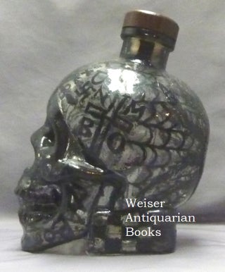 A skull shaped glass vodka bottle, heavily decorated with diabolic sigils and symbois by artist Barry William Hale. One of only 7 "Bottles of Beelzebub" that he produced thus, each obviously unique.